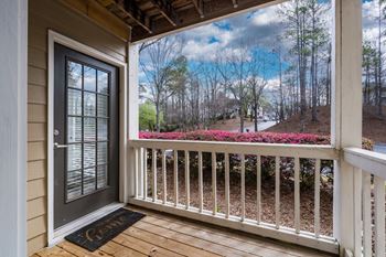 A wood-floored front patio with white railing.